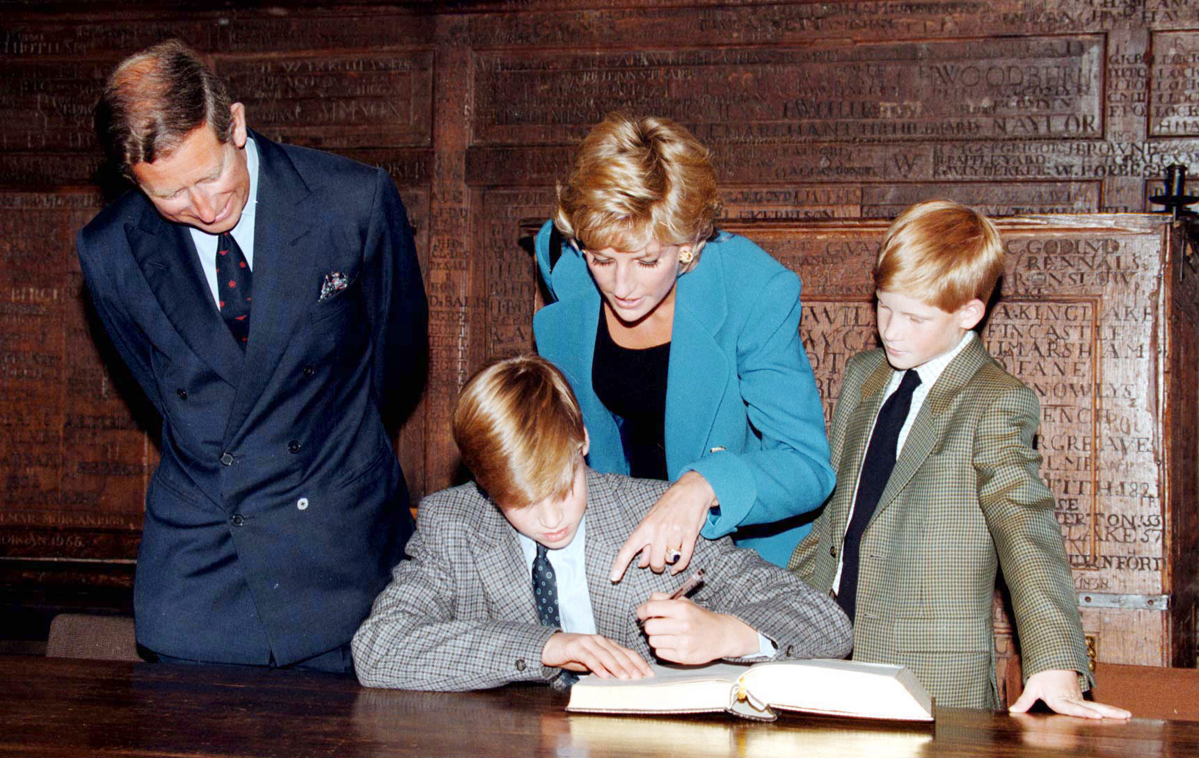 Prince William signing a book at Eton college on his first day with Prince Charles, Prince Harry and Princess Diana looking on