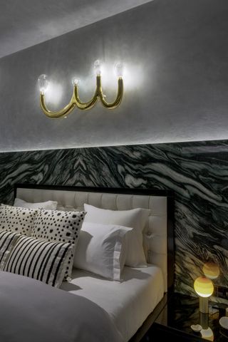 master bed with dramatic headboard and bedroom lighting