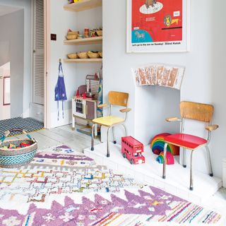 white kids' room with wooden chairs, a colourful rug and artwork