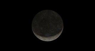the resting crescent of an intricately grey planet, shadowed on top.