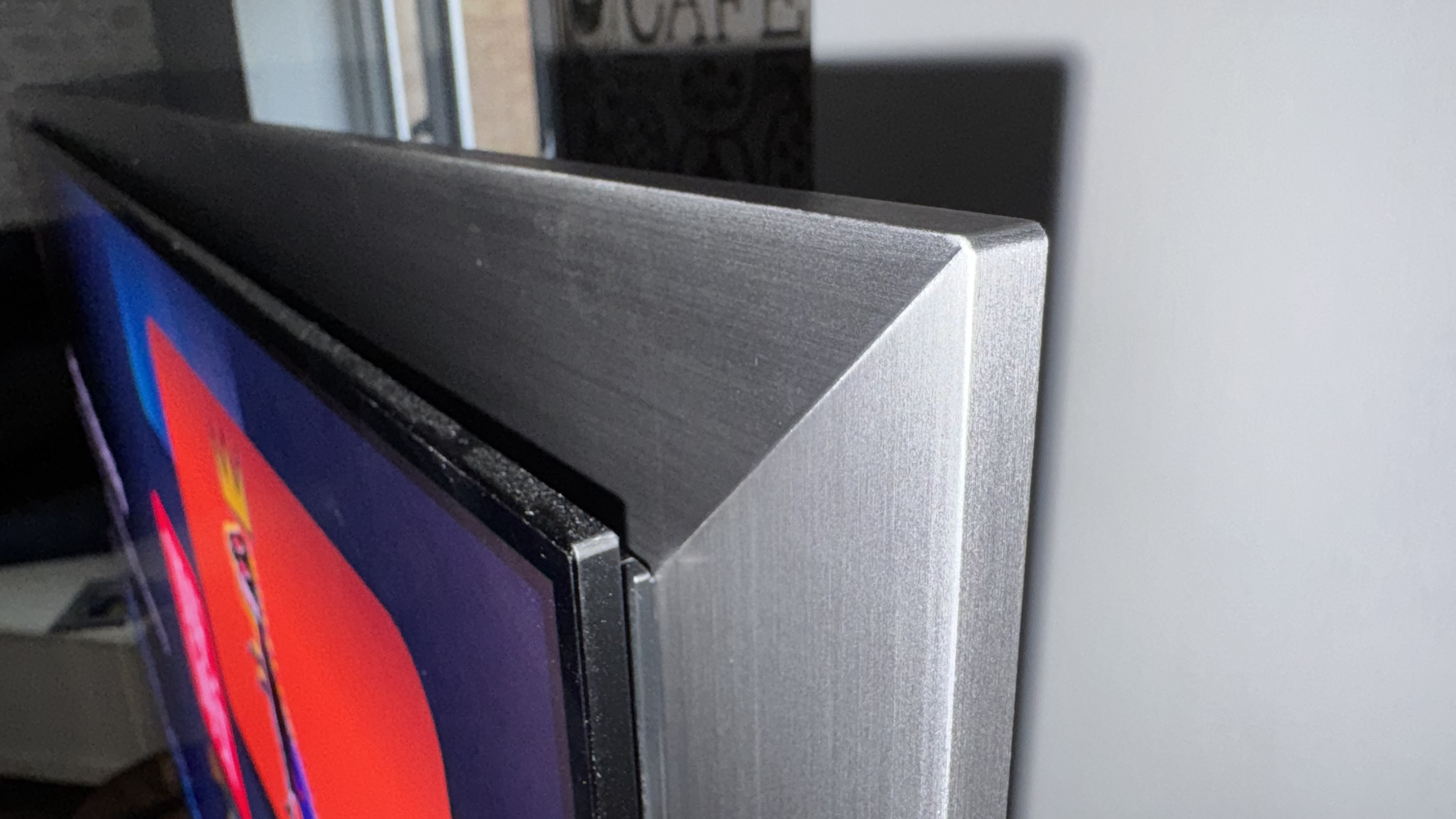 The Samsung S99H/S95H TV's corner, showing the thickness of the new silver frame design, which is much deeper than the OLED panel