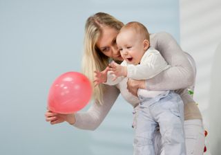 Mother and baby playing with a red balloon