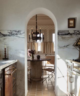 Marble kitchen with arched doorway that looks into a breakfast nook