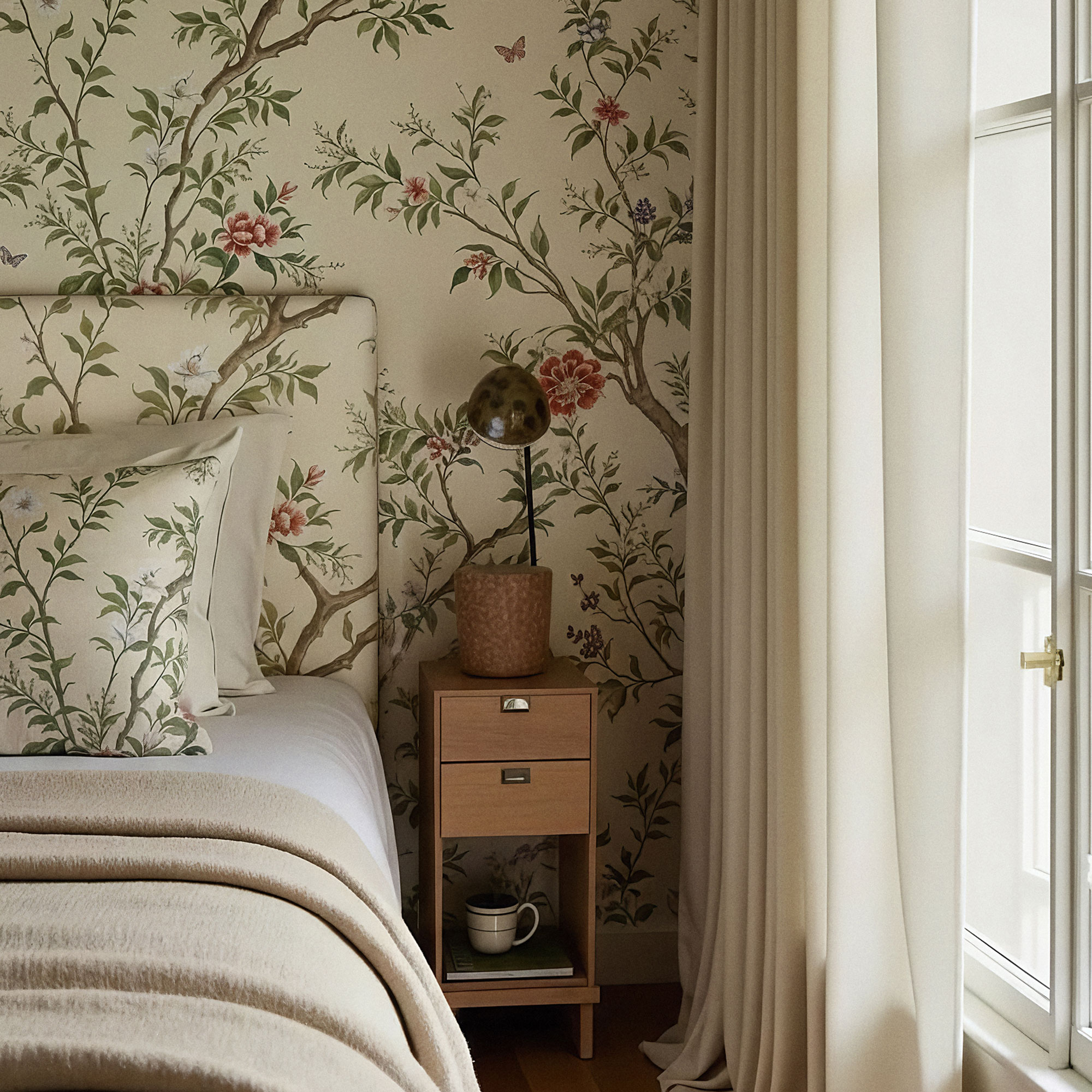 White and green floral wallpaper with matching headboard and cushions.
