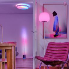 Multicoloured smart wall, standing and ceiling lights in white room with portrait photography on walls