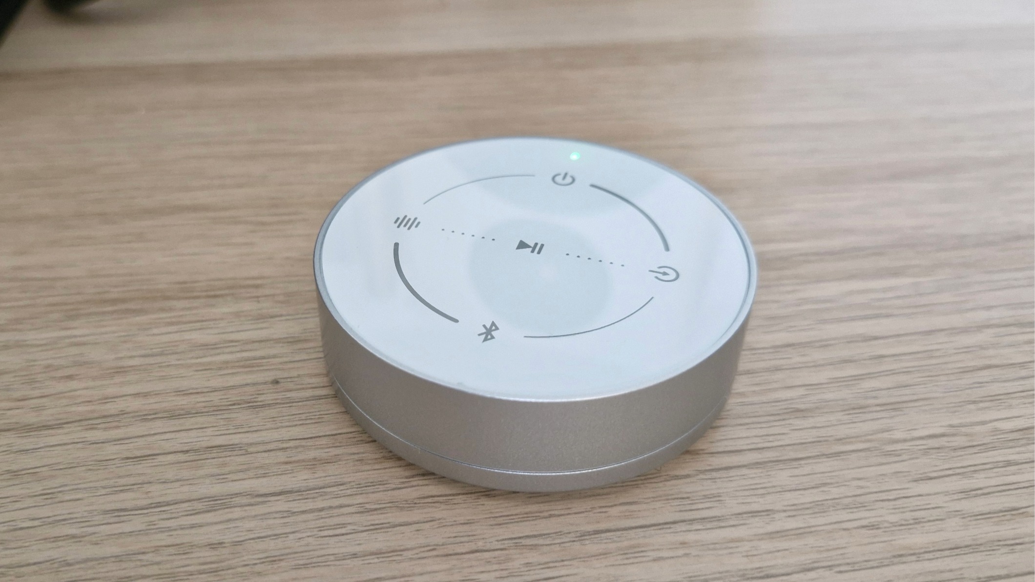 Closeup of emote control puck of the Edifier S880DB MKII active bookshelf speakers, on a wooden surface.