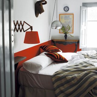 bedroom with red lamp and bed with blanket