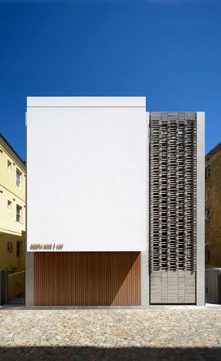 An exterior view of a white residential building with stacked wooden crate design