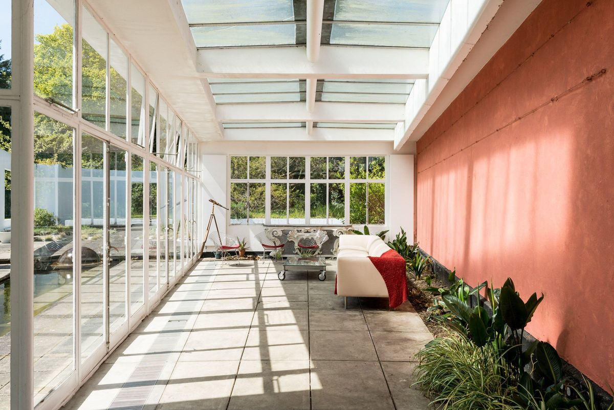 A conservatory has a sofa and a red wall