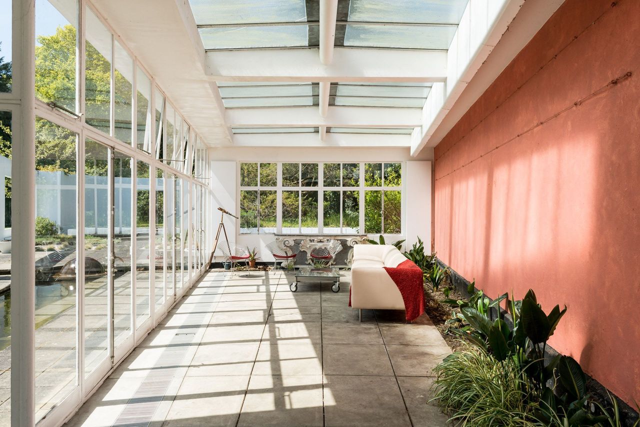 A conservatory has a sofa and a red wall