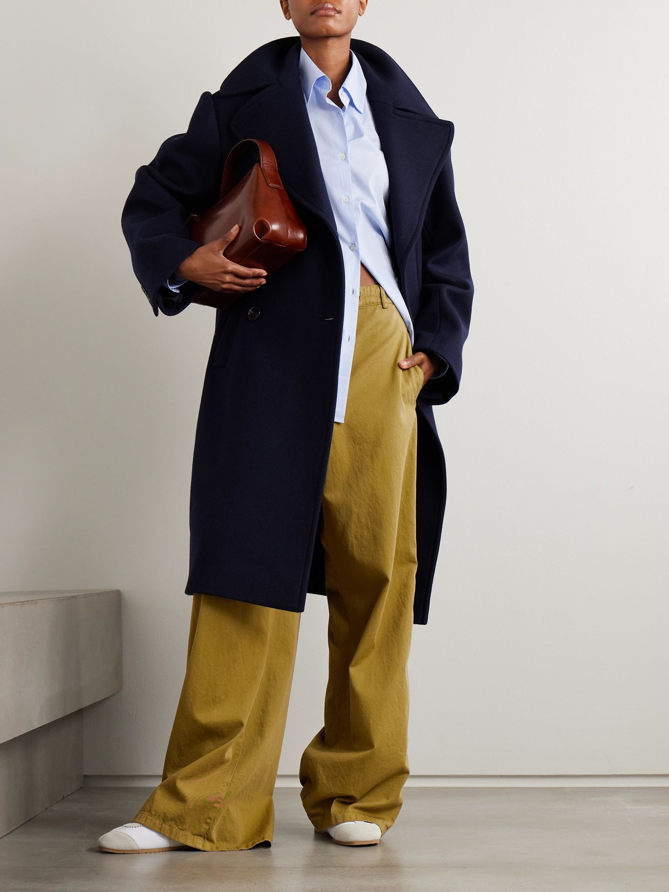 a model wearing brown trousers, a blue shirt and navy coat
