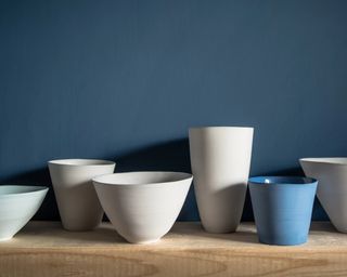 A collection of blue and white ceramic vessels on a wooden shelf