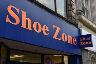 A close up of a Shoezone sign above a shop