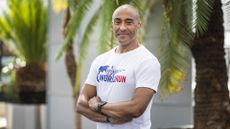 Sprinter legend Colin Jackson posing in a Wings for Life t-shirt in front on palm trees