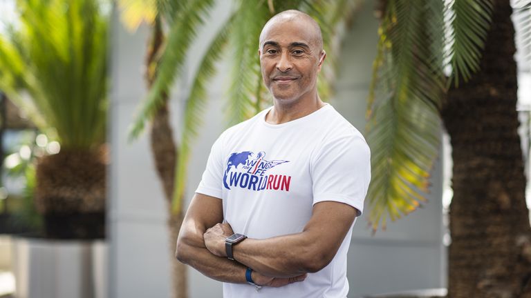 Sprinter legend Colin Jackson posing in a Wings for Life t-shirt in front on palm trees