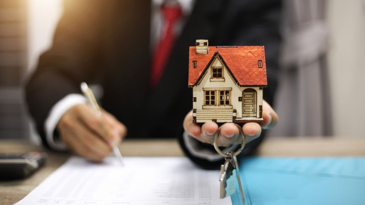 A conveyancer holding up a toy figurine house