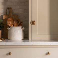 beige kitchen cabinets with brass understated drawer pulls and marble worktops