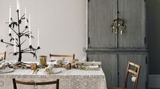 Christmas table with taupe floral tablecloth, rustic wood chairs, and white dinnerware