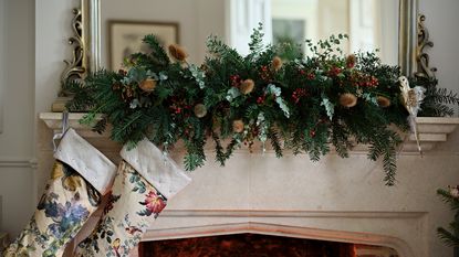 A mantelpiece decorated with fresh pine, eucalyptus and winter berries