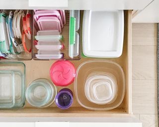 A drawer filled with an assortment of plastic containers and lids