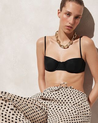 a model wears a black balconette bikini top with polka dot pants