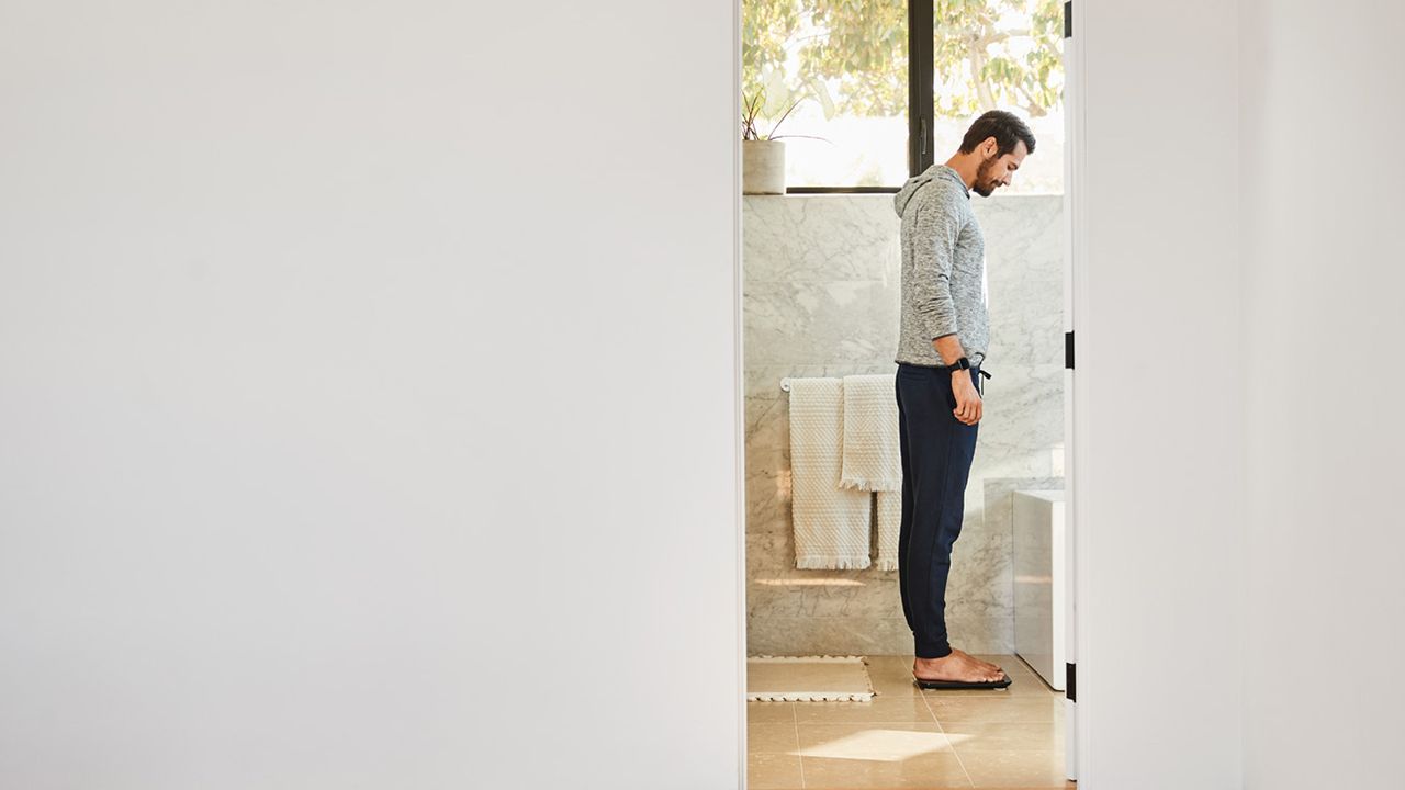 Fitbit Aria Air review: men looking at bathroom scale