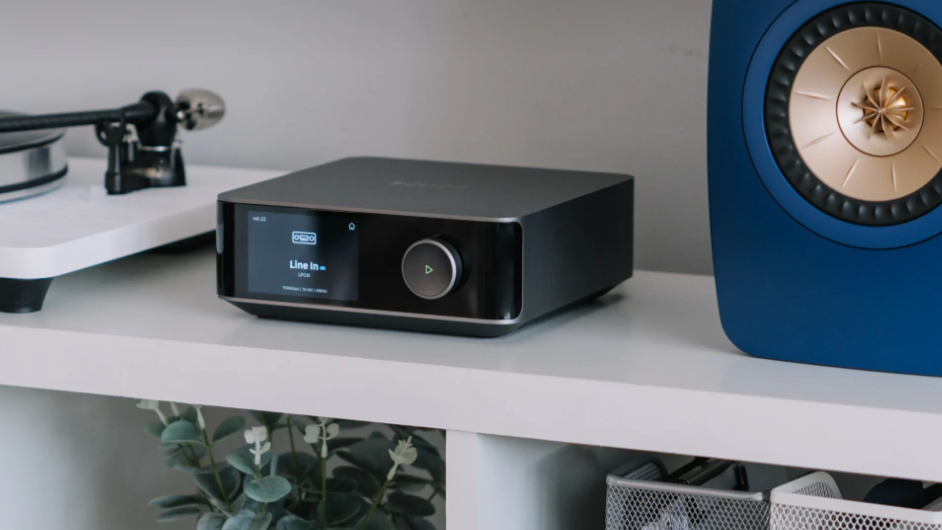 The Wiim Amp Ultra sitting between a speaker and a turntable.