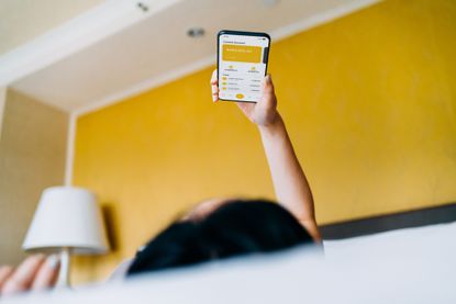 Woman managing money on smartphone while lying on bed