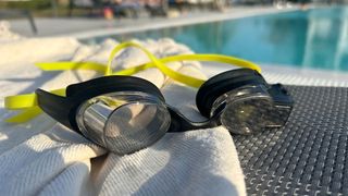 FORM Smart Swim 2 swimming goggles next to an outdoor pool