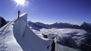 Mountaineer climbing along a snowy cornice, very exposed