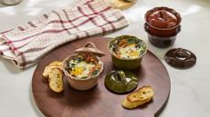 Green, pink and red scalloped ramekins on a round wooden cutting board
