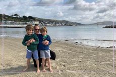 Mum stood on a beach hugging her two small children