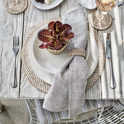 White dinnerware set displayed on top of round rattan placemat on dining table