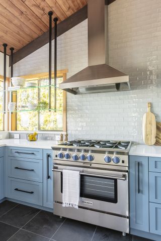 kitchen with blue cabinets and brick bone backsplash by Interiors by Popov
