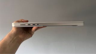 Image shows a side view of the MacBook Pro M1 Pro 2021 held in someone's hand.