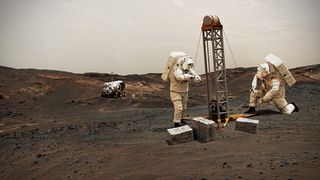 astronauts in space suits construct a short tower on the brown/red surface of mars. supply boxes lay about. a rover is parked in the distance.