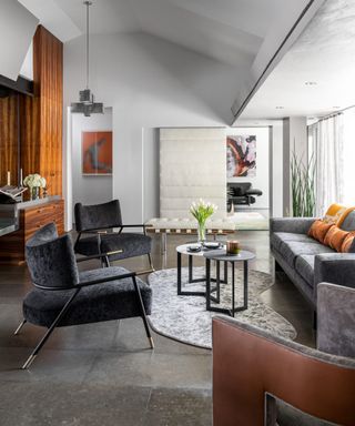 Living room with gray sofa and armchairs and coffee table on curved light gray area rug