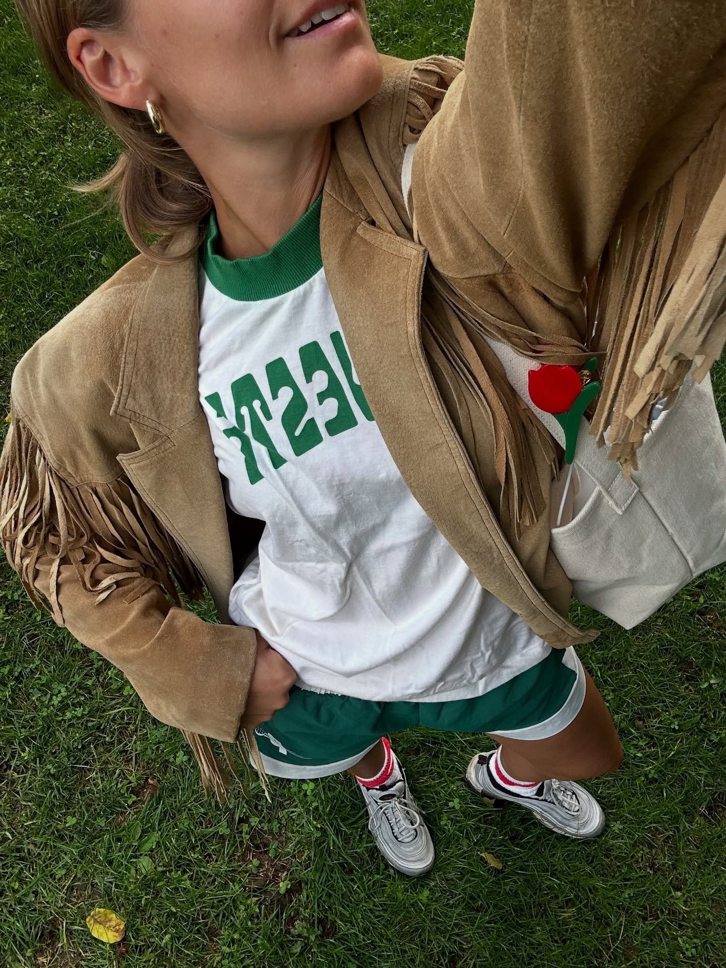 @madmadder wearing a fringe jacket with a green-and-white tee and shorts.