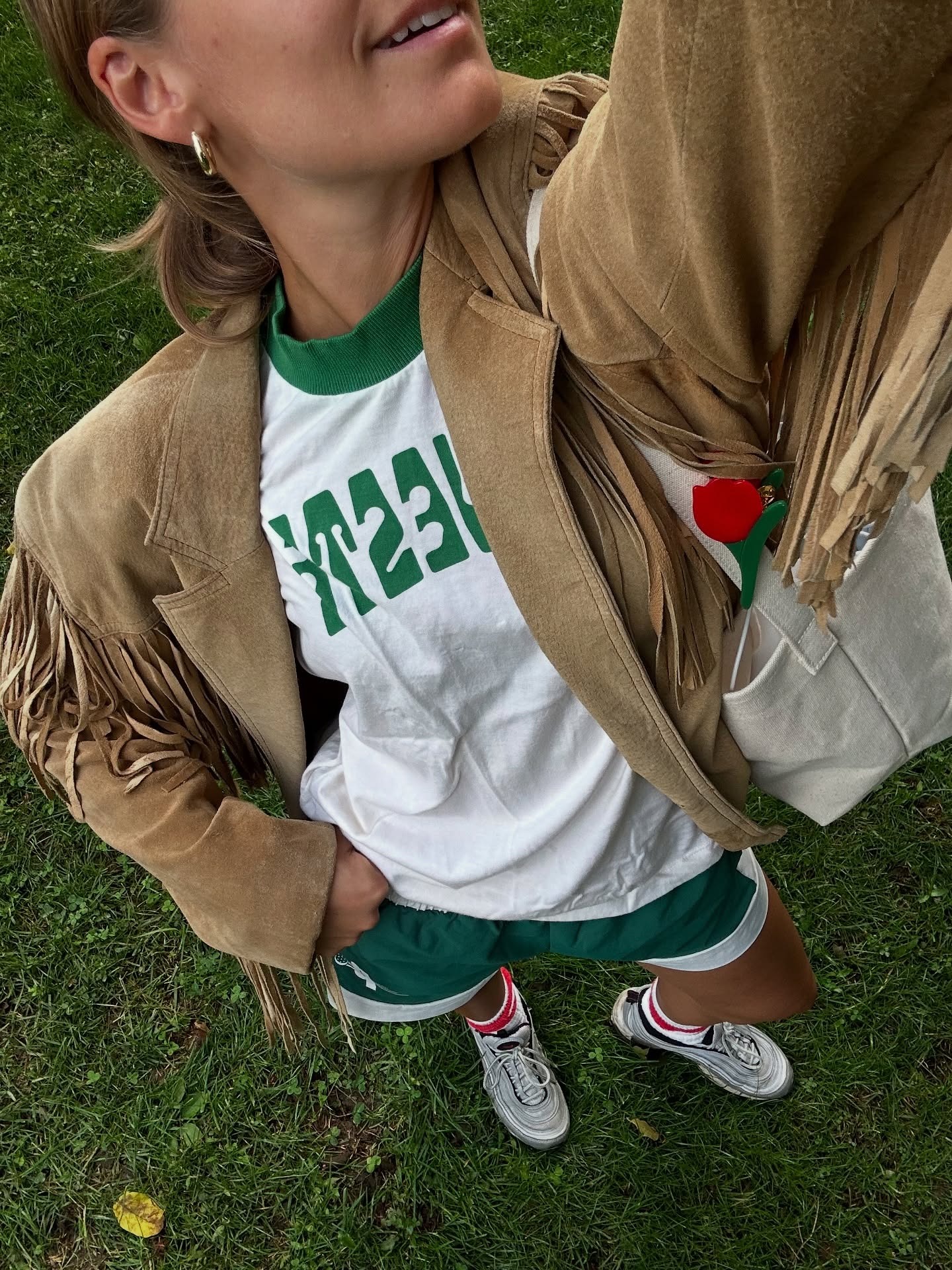@madmadder wearing a fringe jacket with a green-and-white tee and shorts.
