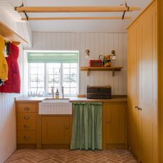 utility room with yellow cabinets, a butler sink, open shelving and laundry area