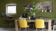 Stylish dining room with vase of long lilac stems on wooden table