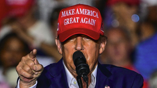 Former US President and Republican presidential candidate Donald Trump, wearing a red and white MAGA cap, gestures as he speaks ahead of his RNC 2024 Republican National Convention speech in Milwaukee