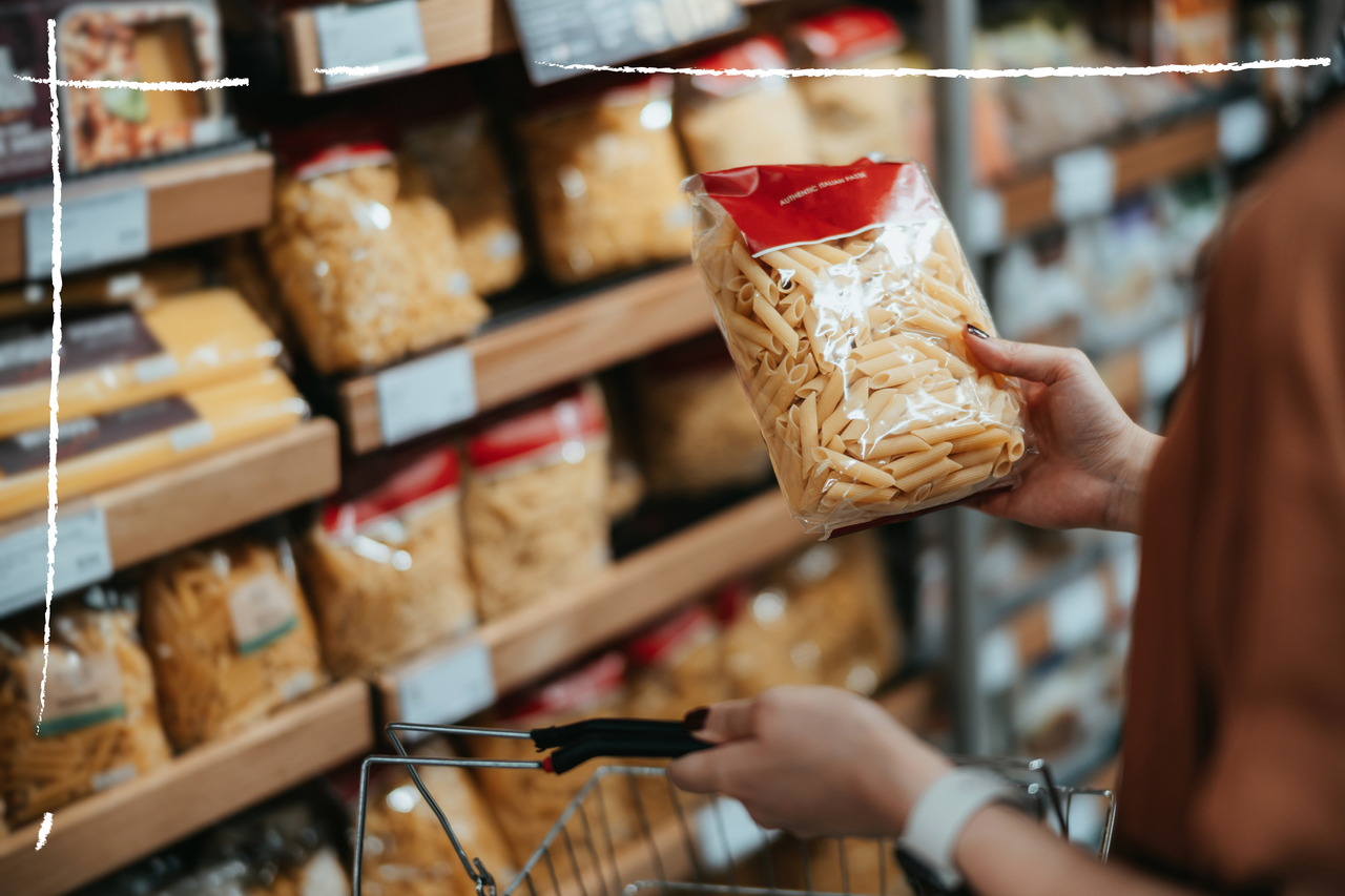 Woman picking up a packet of pasta in the supermarket to start carb cycling