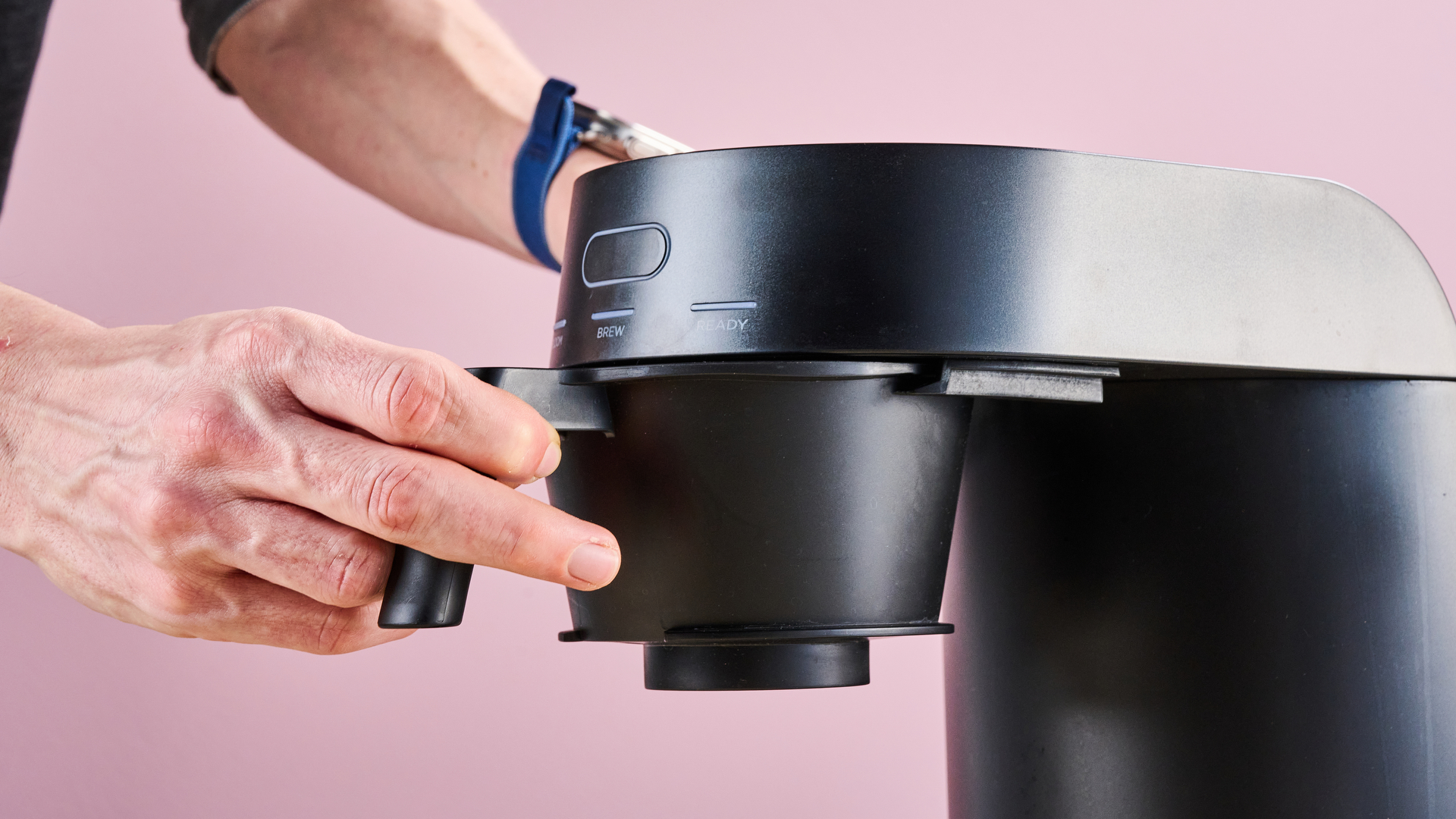 A man's hands insert the filter basket into the Ratio Four.