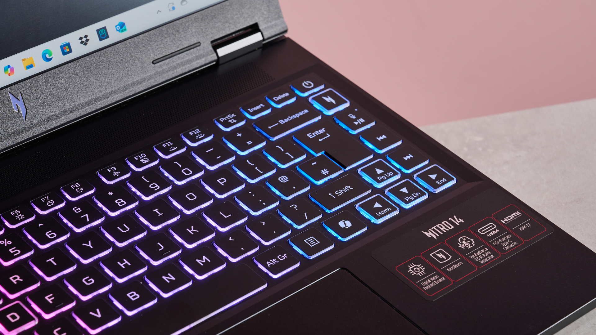 The Acer Nitro 14 compact gaming laptop photographed on a coral background.