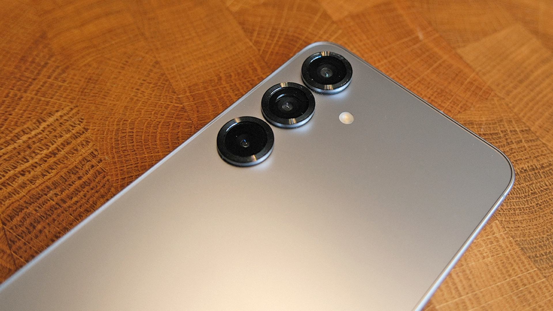 Samsung Galaxy S25 Plus smartphone face down on wooden surface showing rear camera array