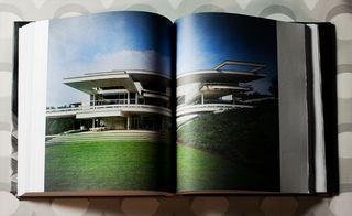 A double page of the book which shows a garden that leads to a large house.