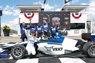 Race car driver and team celebrating a win next to the car