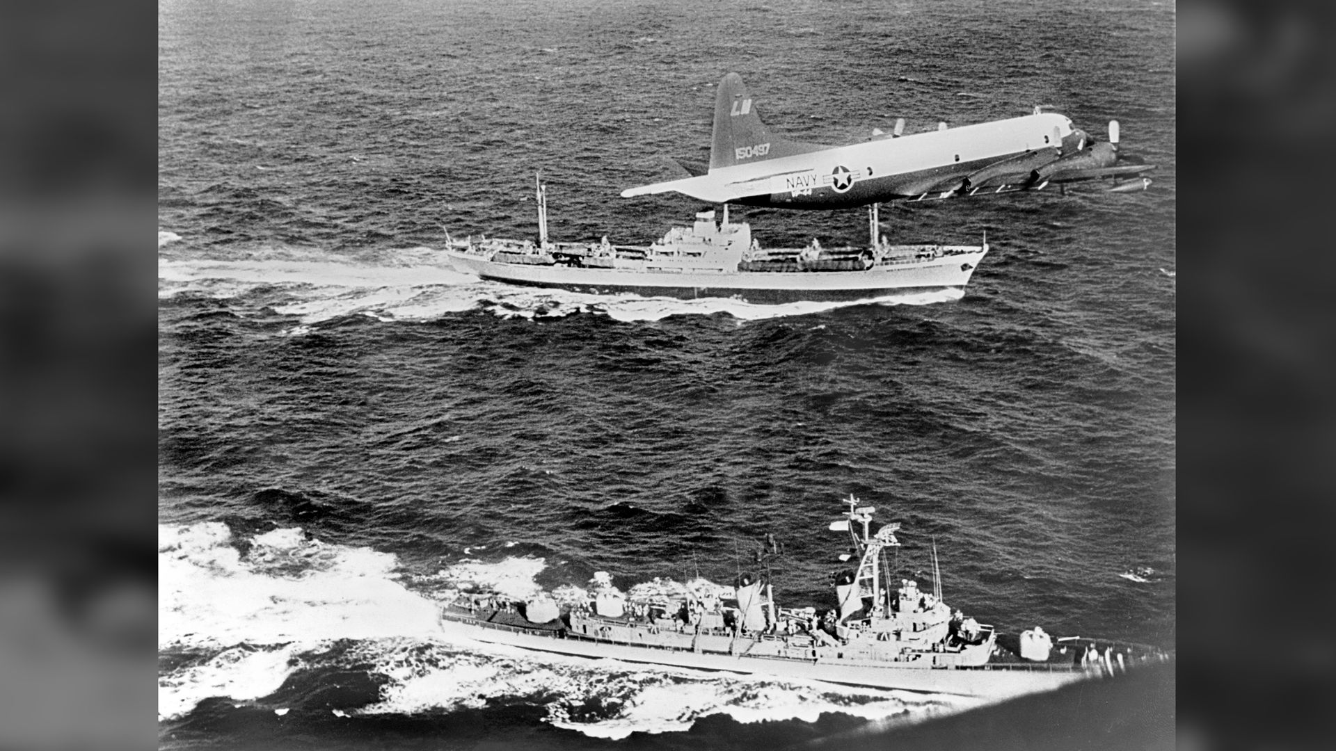 A U.S. plane and destroyer escort a Soviet freighter suspected of carrying nuclear missiles as it leaves Cuba during the Cuban Missile Crisis.