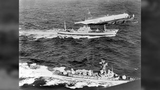 A U.S. plane and destroyer escort a Soviet freighter suspected of carrying nuclear missiles as it leaves Cuba during the Cuban Missile Crisis.